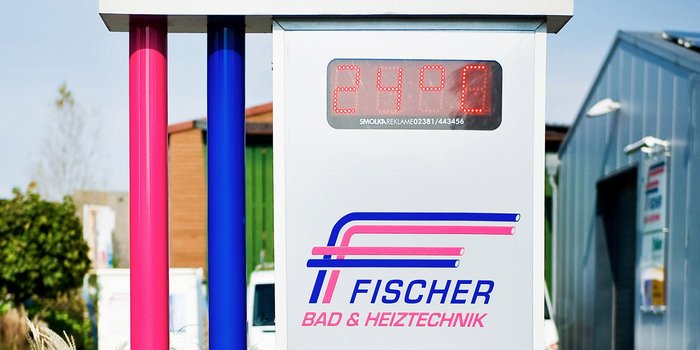 Ein helles Schild mit der Aufschrift 'FISCHER BAD & HEIZTECHNIK' und einer digitalen Anzeige von 24,9 Grad Celsius.