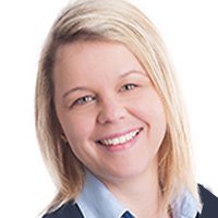 Die Frau hat ein freundliches Lächeln und kurze, blonde Haare, während sie in die Kamera schaut.