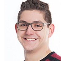 Der Mann hat ein breites Lächeln und trägt eine modische Brille, während er in die Kamera schaut.