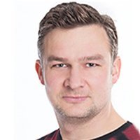 Ein Mann mit kurzen, grauen Haaren und einem leichten Bart lächelt freundlich in die Kamera.